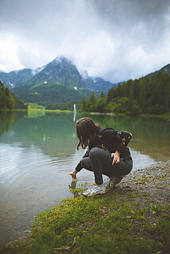 Young woman crouching by lake