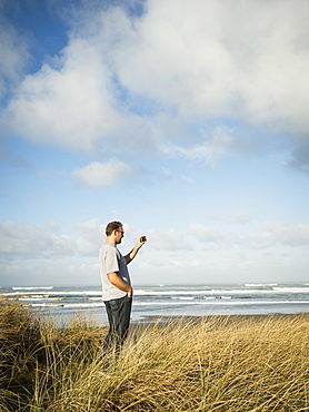 Mid adult man taking photograph, Rockaway Beach, Oregon