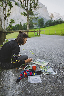 Young woman painting mountains on road