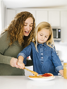 Woman making peanut butter and jelly sandwich with her daughter