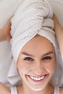 Portrait of smiling woman with head wrapped in towel