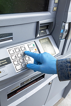 Close-up of gloved hand on keypad of ATM machine