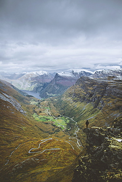 Man standing on Dalsnibba mountain overlooking valley in Geiranger, Norway