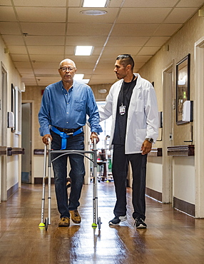 Doctor helping senior man use walking frame