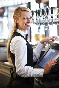 Young waitress using computer at restaurant counter