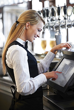 Young waitress using computer at restaurant counter