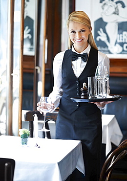 Portrait of young waitress holding tray and wine glasses