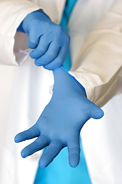 Person putting on blue surgical gloves