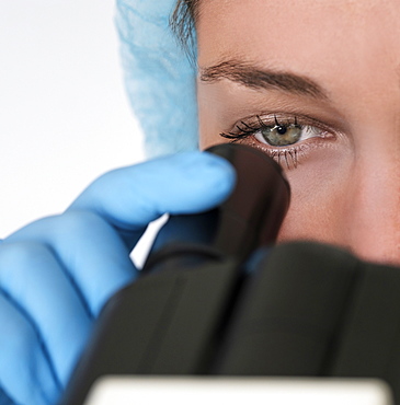 Laboratory technician looking through microscope