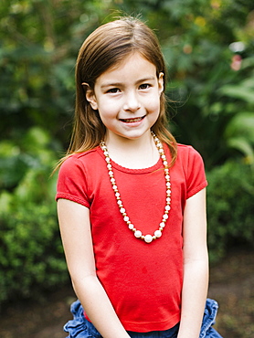 USA, California, Orange County, Portrait of smiling girl (6-7) wearing bead necklace