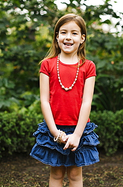 USA, California, Orange County, Portrait of smiling girl (6-7) wearing bead necklace