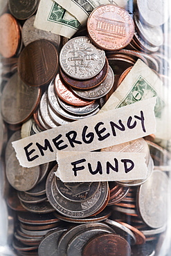 Close-up of coins and banknotes in jar labeled Emergency Found