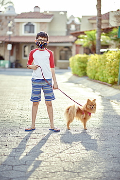 Mexico, Zapopan, Boy with face mask walking dog