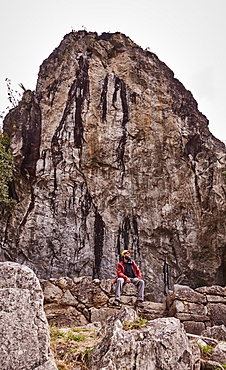 Peru, Machu Pichu, Man sitting in front of rock formation