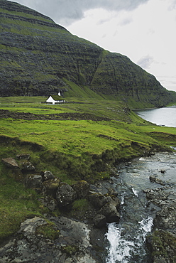 Denmark, Small church in green landscape with mountains and sea