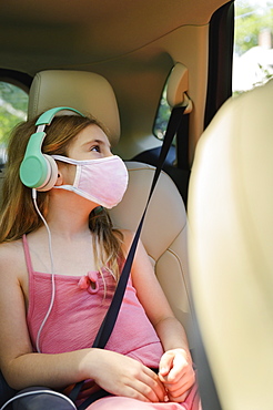 Masked girl (6-7) listening to music in car