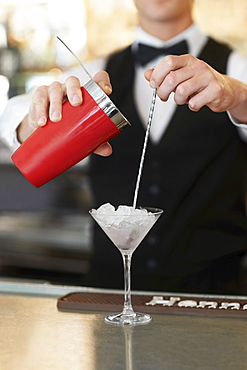 Young bartender pouring cocktail 