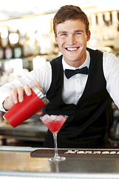 Young bartender pouring cocktail 