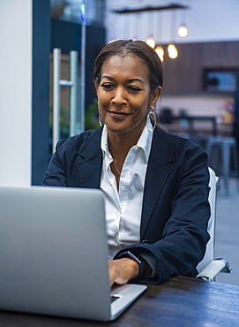 Smiling businesswoman working on laptop at desk in office