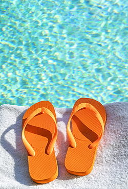 Orange flip flops on towel at poolside