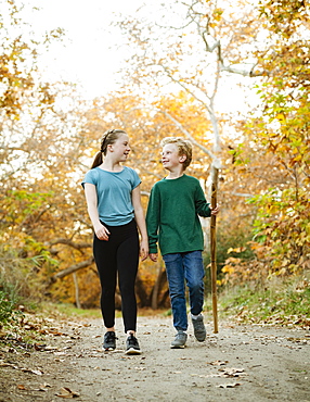 United States, California, Mission Viejo, Boy (10-11) and girl (12-13) walking on footpath in forest