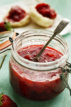 Jar of homemade strawberry preserve with teaspoon