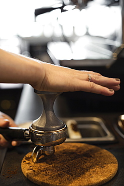 Coffee shop barista removing coffee grounds, close-up