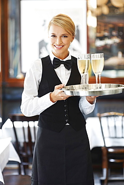 Portrait of waitress holding champagne flutes on tray