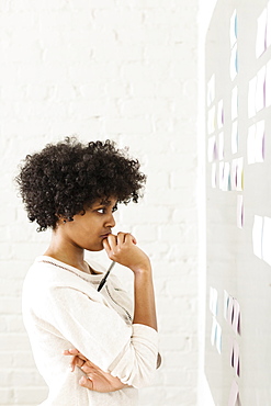 Young woman reading adhesive notes on wall