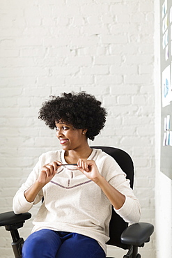 Portrait of young woman sitting in office chair looking away