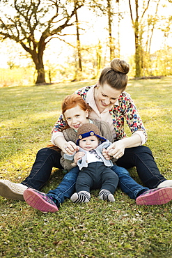 Portrait of mid adult mother, daughter and baby son in park