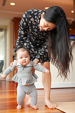 Mother helping baby girl to walk