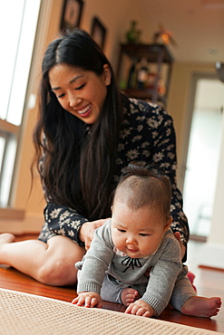 Baby girl sitting on floor with mother