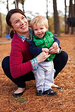 Laughing mother tickling son in park