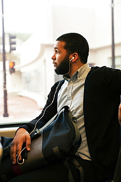 Young man traveling on light train wearing earphones