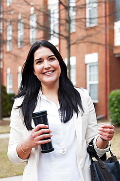 Young woman carrying travel mug