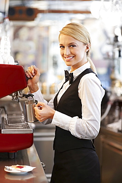 Female barista steaming milk