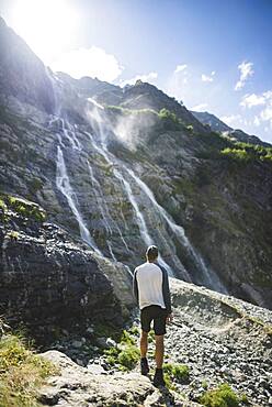 Russia, Karachay-Cherkessia, Arkhyz, Man standing near Sofiyskiye Vodopady waterfall in Caucasus Mountains