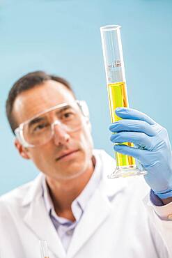 Scientist looking at yellow liquid in measuring beaker