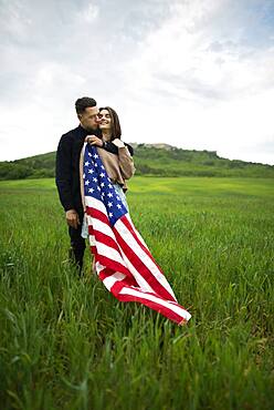 Young couple with American flag in wheat field