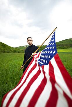 Young man with American flag in wheat field