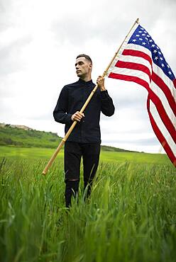 Young man with American flag in wheat field