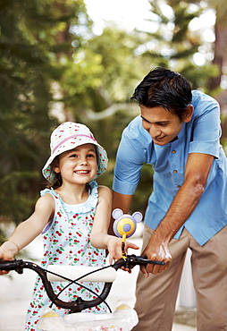 Man assisting girl (6-7) riding bicycle