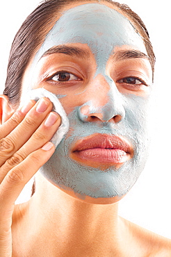 Close-up of woman removing blue facial mask