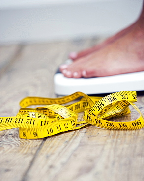 Tape measure next to woman standing on scale