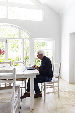 Senior man working on laptop computer at home