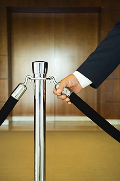 Man holding velvet rope, close up