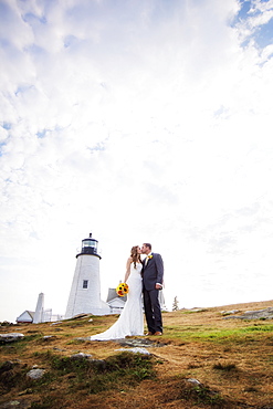 Portrait of married couple kissing, lighthouse in background, USA, Maine, Bristol 