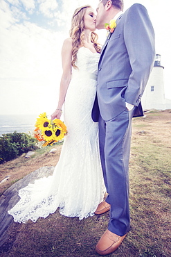 Portrait of married couple kissing, lighthouse in background, USA, Maine, Bristol 