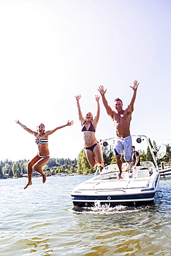 Young people jumping to lake from motorboat, USA, Washington, Bellingham 